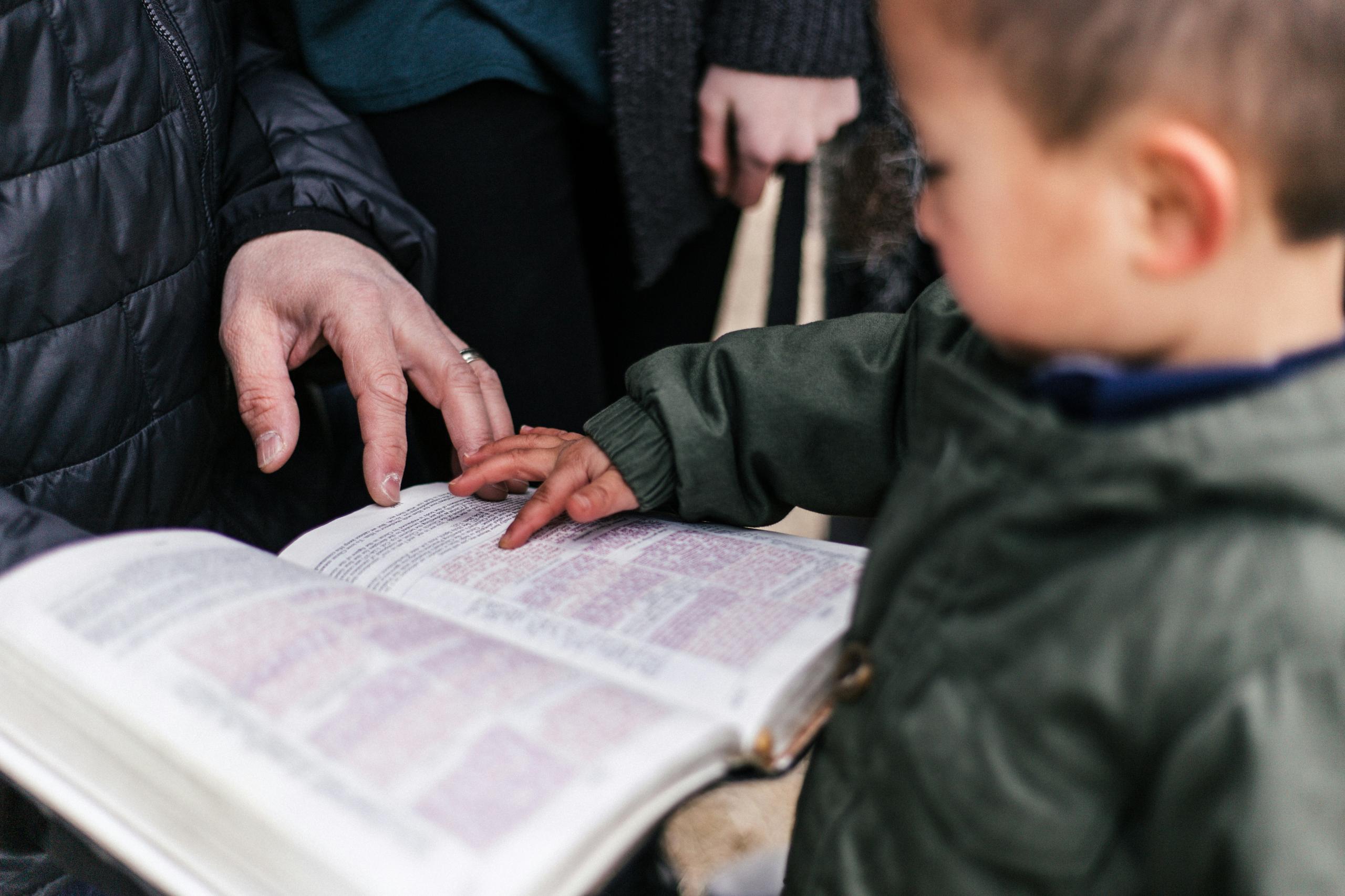 toddler pointing at letters in open book