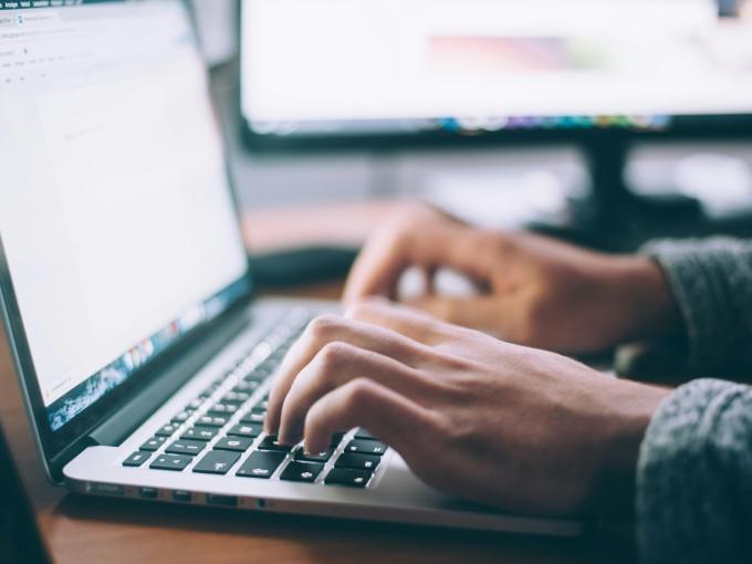 two hands typing on a laptop