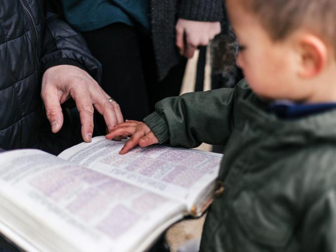 toddler pointing at letters in open book