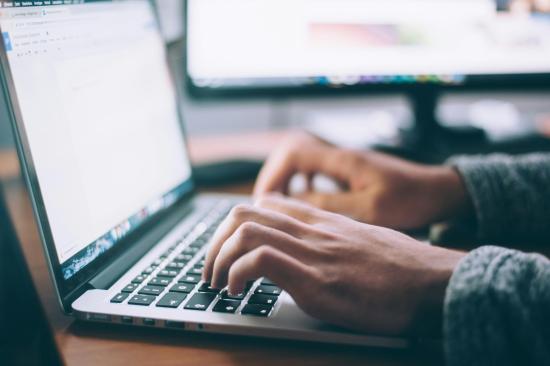 two hands typing on a laptop