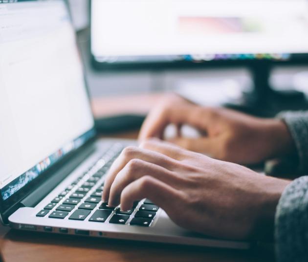 two hands typing on a laptop