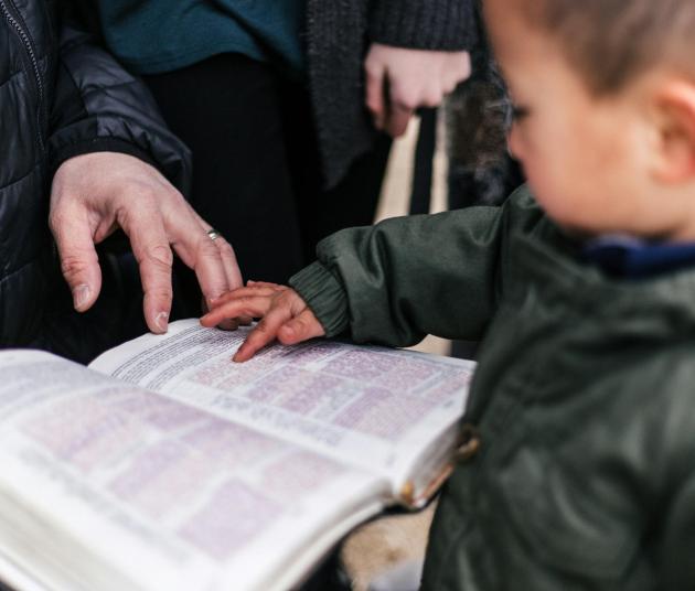 toddler pointing at letters in open book